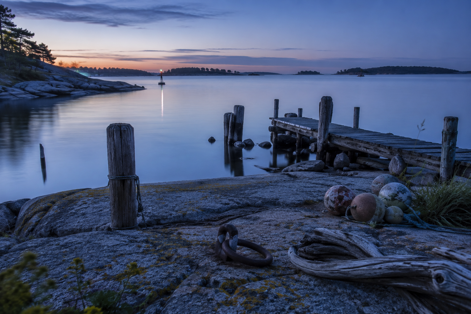 Blue-hour Baltic shoreline with weathered jetty, mooring posts, and traces of long-term coastal use